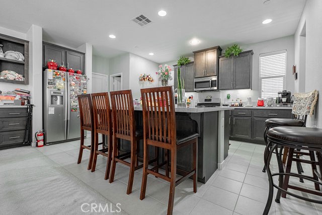 39580 Strada Pozzo Lake Elsinore, CA 92532 - Photo 19 of 67 a kitchen with stainless steel appliances kitchen island granite countertop a table chairs sink and cabinets