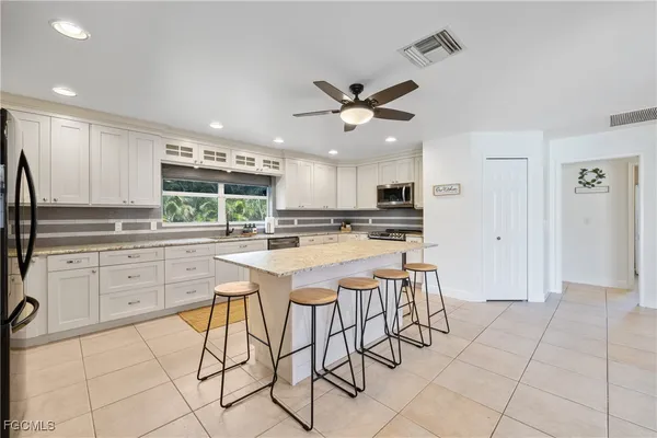 a kitchen with stainless steel appliances kitchen island granite countertop a refrigerator and a sink