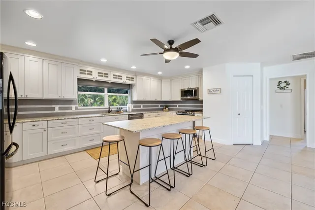a kitchen with stainless steel appliances kitchen island granite countertop a refrigerator and a sink