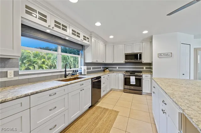 a kitchen with stainless steel appliances kitchen island granite countertop a refrigerator and white cabinets