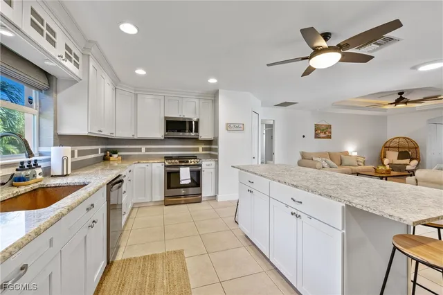 a kitchen with kitchen island granite countertop lots of white cabinets a sink and appliances