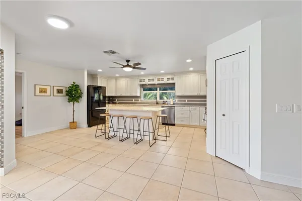 a kitchen with stainless steel appliances kitchen island granite countertop a refrigerator a stove a sink a dining table and chairs