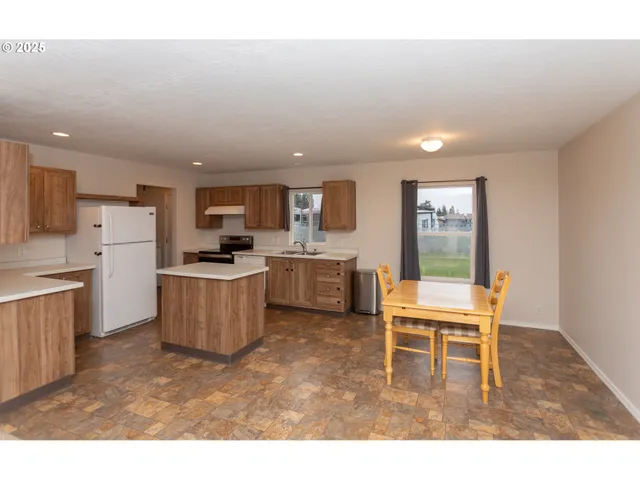 a kitchen with a dining table chairs and refrigerator