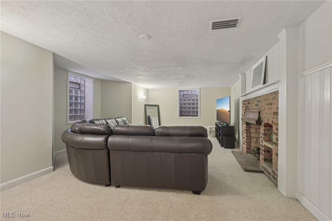 17024 Fernway Road Cleveland, OH 44120 - Photo 39 of 46 Recreation Room featuring a textured ceiling, carpet floors, and a fireplace