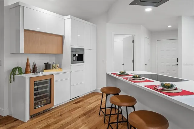 a white kitchen with a stove and chairs