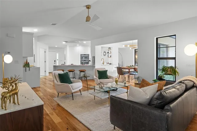 a living room with furniture kitchen view and a large window