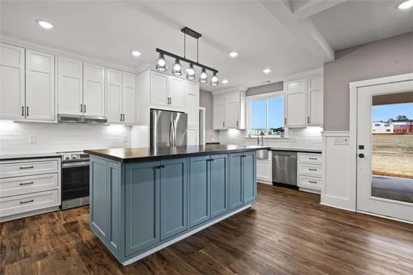 a kitchen with stainless steel appliances granite countertop a stove top oven a sink dishwasher a dining table and chairs with wooden floor