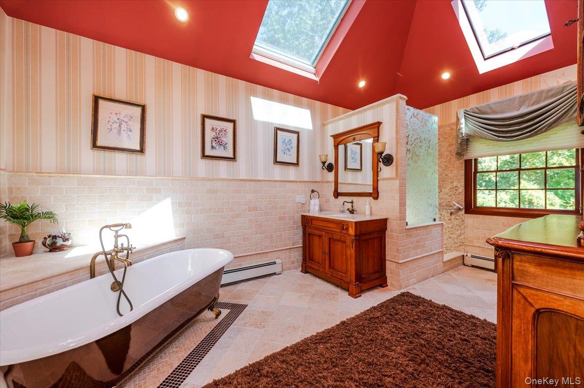 155 Jennings Road Cold Spring Harbor, NY 11724 - Photo 20 of 36 Bathroom with a freestanding bath, recessed lighting, vanity, a baseboard radiator, and a skylight