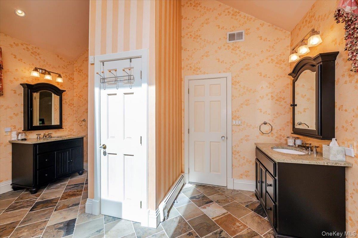 155 Jennings Road Cold Spring Harbor, NY 11724 - Photo 25 of 36 Bathroom featuring two vanities, wallpapered walls, vaulted ceiling, and a baseboard radiator