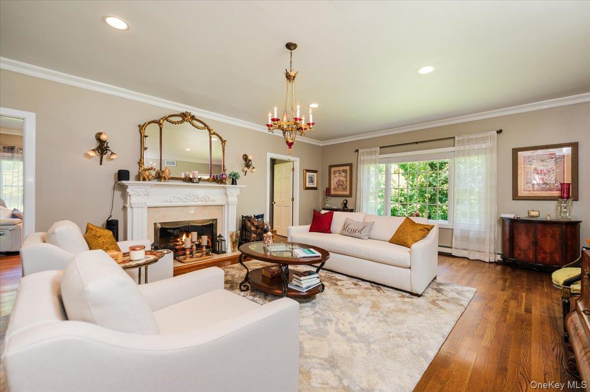 155 Jennings Road Cold Spring Harbor, NY 11724 - Photo 8 of 36 Living area featuring ornamental molding, a warm lit fireplace, wood finished floors, recessed lighting, and a chandelier