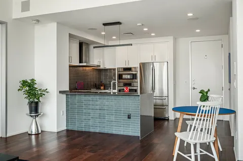a kitchen with stainless steel appliances wooden floor and a refrigerator