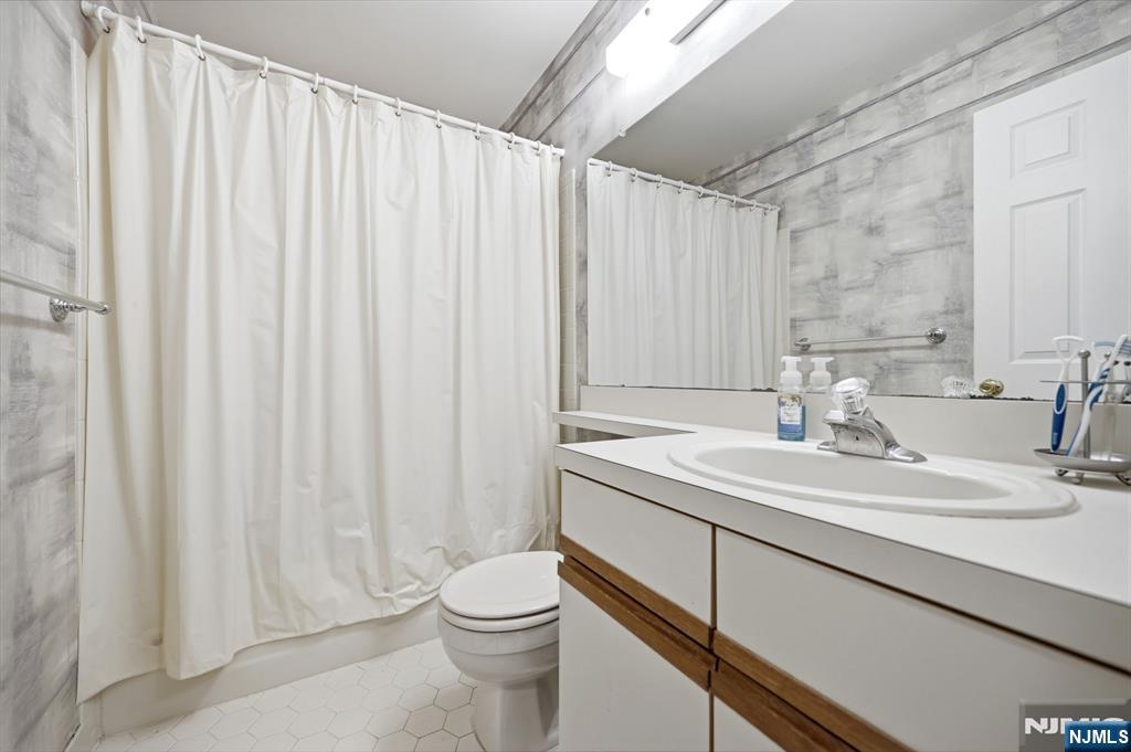 475 Quince Court Mahwah, NJ 07430 - Photo 24 of 27 a bathroom with a sink a toilet and shower curtain