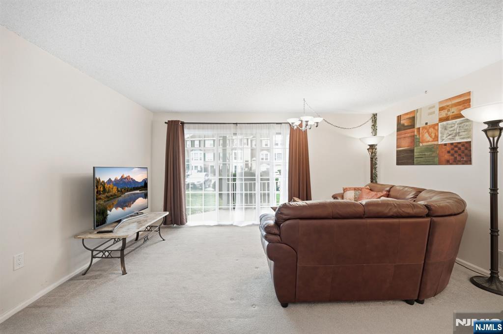 475 Quince Court Mahwah, NJ 07430 - Photo 10 of 27 a living room with furniture a flat screen tv and a floor to ceiling window
