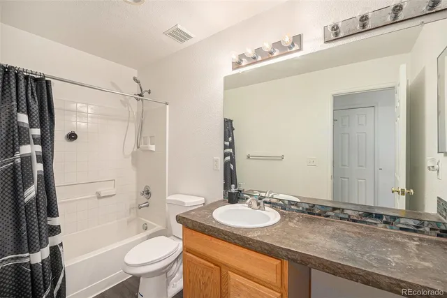 a bathroom with a granite countertop sink toilet mirror and shower