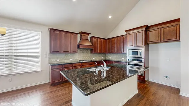 a kitchen with stainless steel appliances granite countertop a sink refrigerator and cabinets