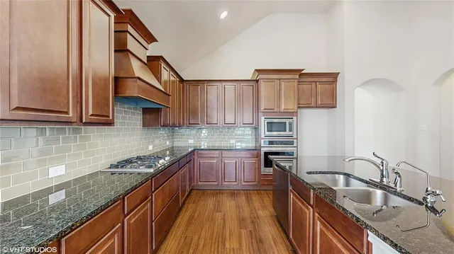 a kitchen with stainless steel appliances granite countertop a sink and dishwasher a stove top oven with wooden floor