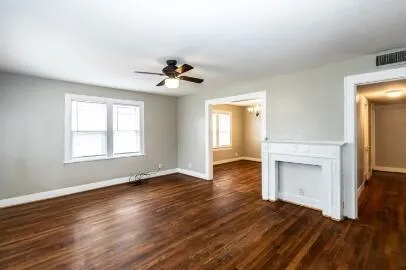 a view of an empty room with a window and wooden floor