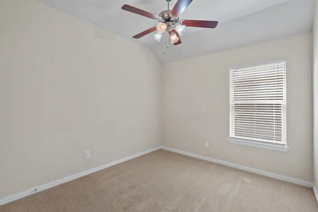 an empty room with a chandelier fan and closet area