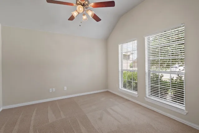 an empty room with windows and fan