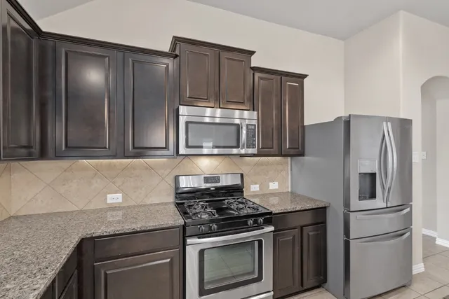 a large kitchen with a large counter top stainless steel appliances and cabinets