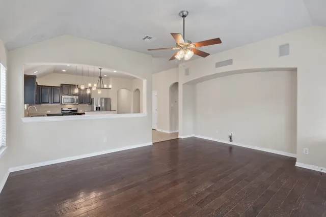 a view of an empty room with window and wooden floor