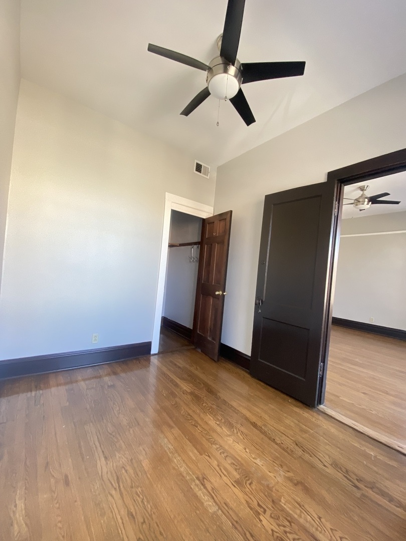2898 North Milwaukee Avenue, Unit 2 Chicago, IL 60618 - Photo 3 of 10 a view of an empty room with wooden floor and a ceiling fan