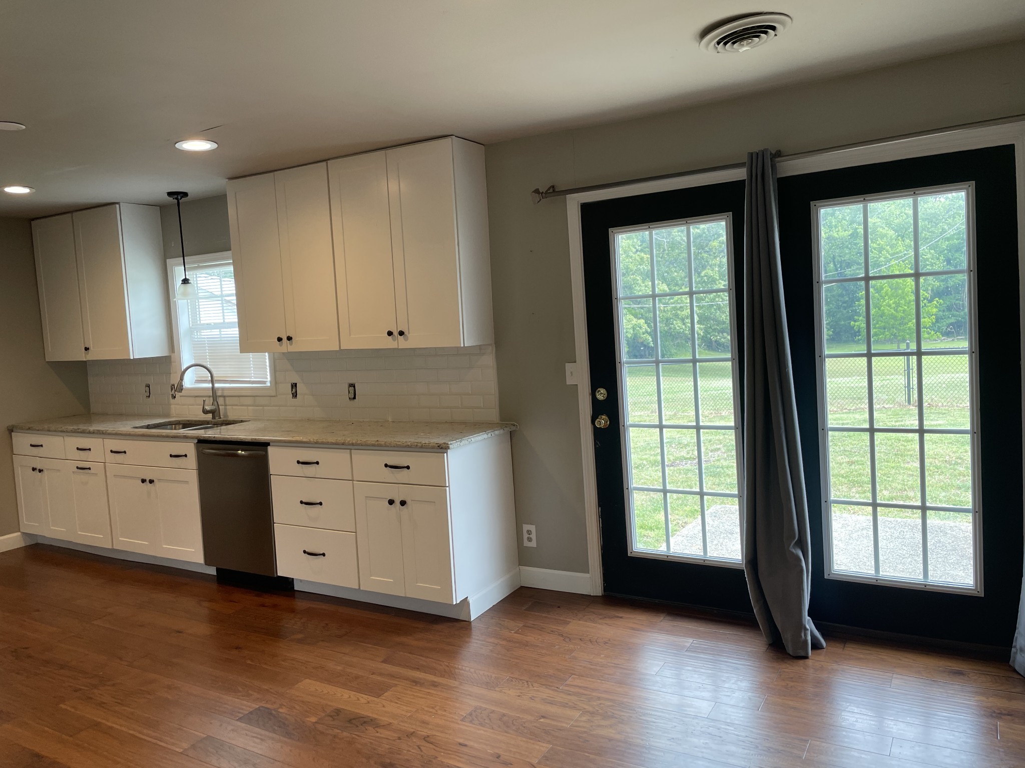 305 Cedar Hill Road Adams, TN 37010 - Photo 20 of 34 a kitchen with granite countertop a stove a sink and white cabinets with wooden floor next to windows