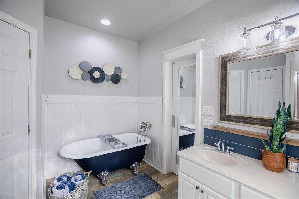 2702 River Ridge Court Granbury, TX 76048 - Photo 11 of 21 Full bathroom featuring wainscoting, vanity, a freestanding tub, and wood finished floors
