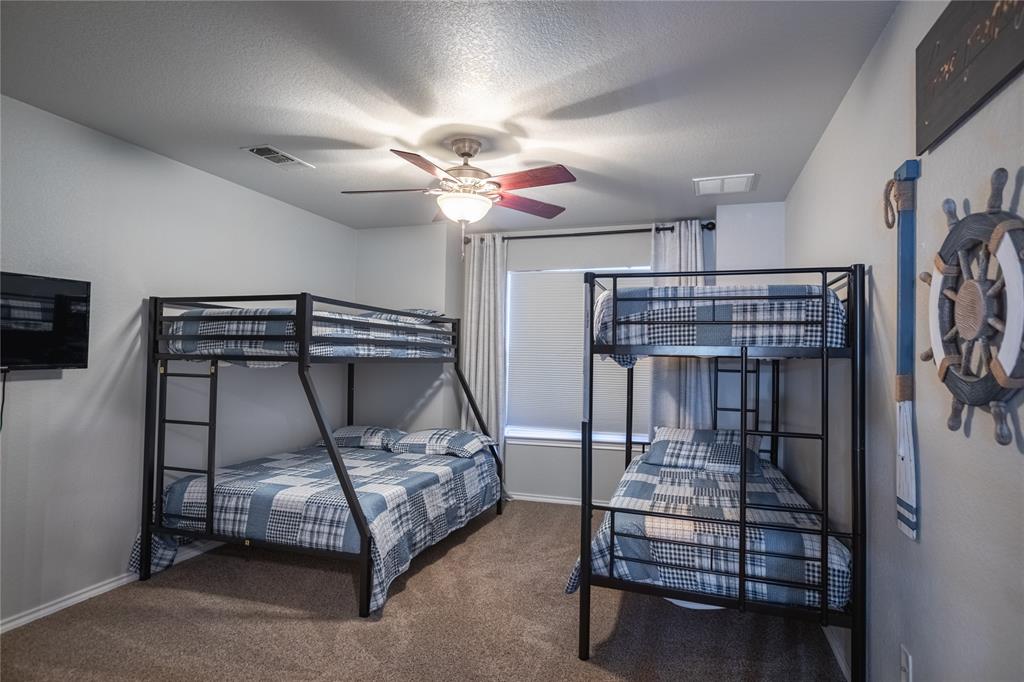2702 River Ridge Court Granbury, TX 76048 - Photo 13 of 21 Bedroom with a textured ceiling, dark colored carpet, and a ceiling fan