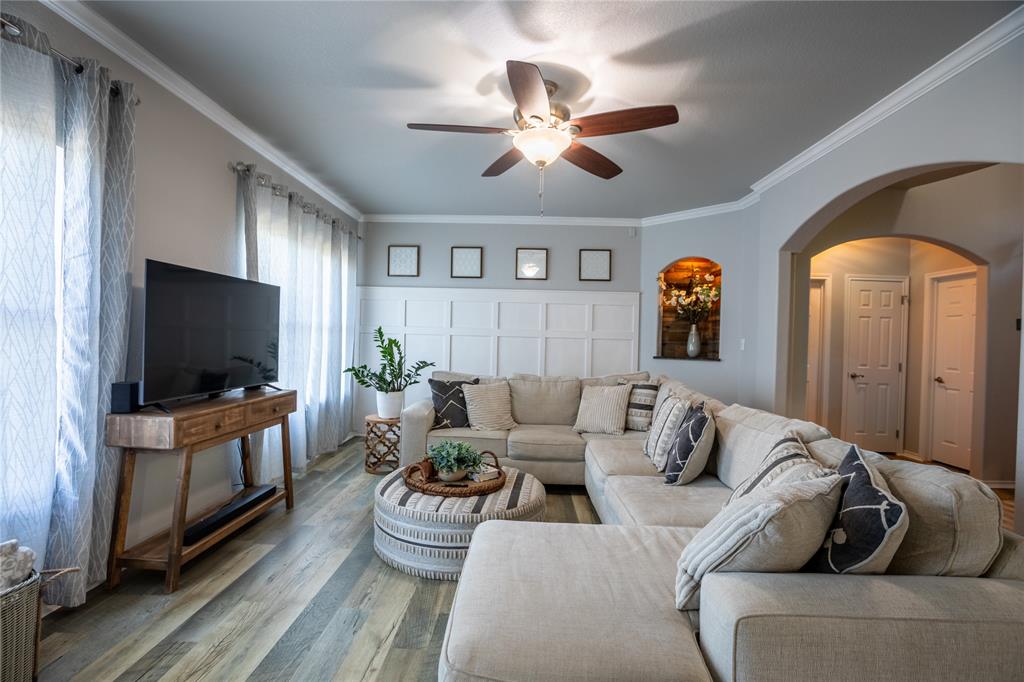 2702 River Ridge Court Granbury, TX 76048 - Photo 4 of 21 Living room with crown molding, arched walkways, a ceiling fan, wood finished floors, and a decorative wall