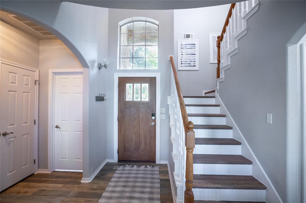 2702 River Ridge Court Granbury, TX 76048 - Photo 7 of 21 Foyer entrance featuring stairs, dark wood-style flooring, a high ceiling, and arched walkways
