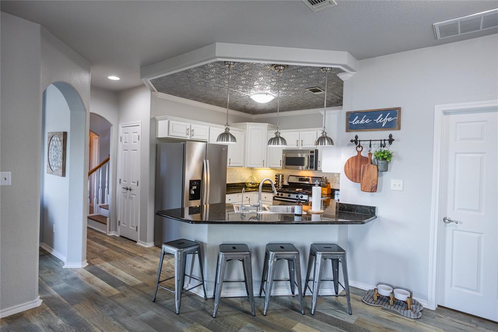 2702 River Ridge Court Granbury, TX 76048 - Photo 8 of 21 Kitchen with a peninsula, arched walkways, a breakfast bar, white cabinetry, and stainless steel appliances
