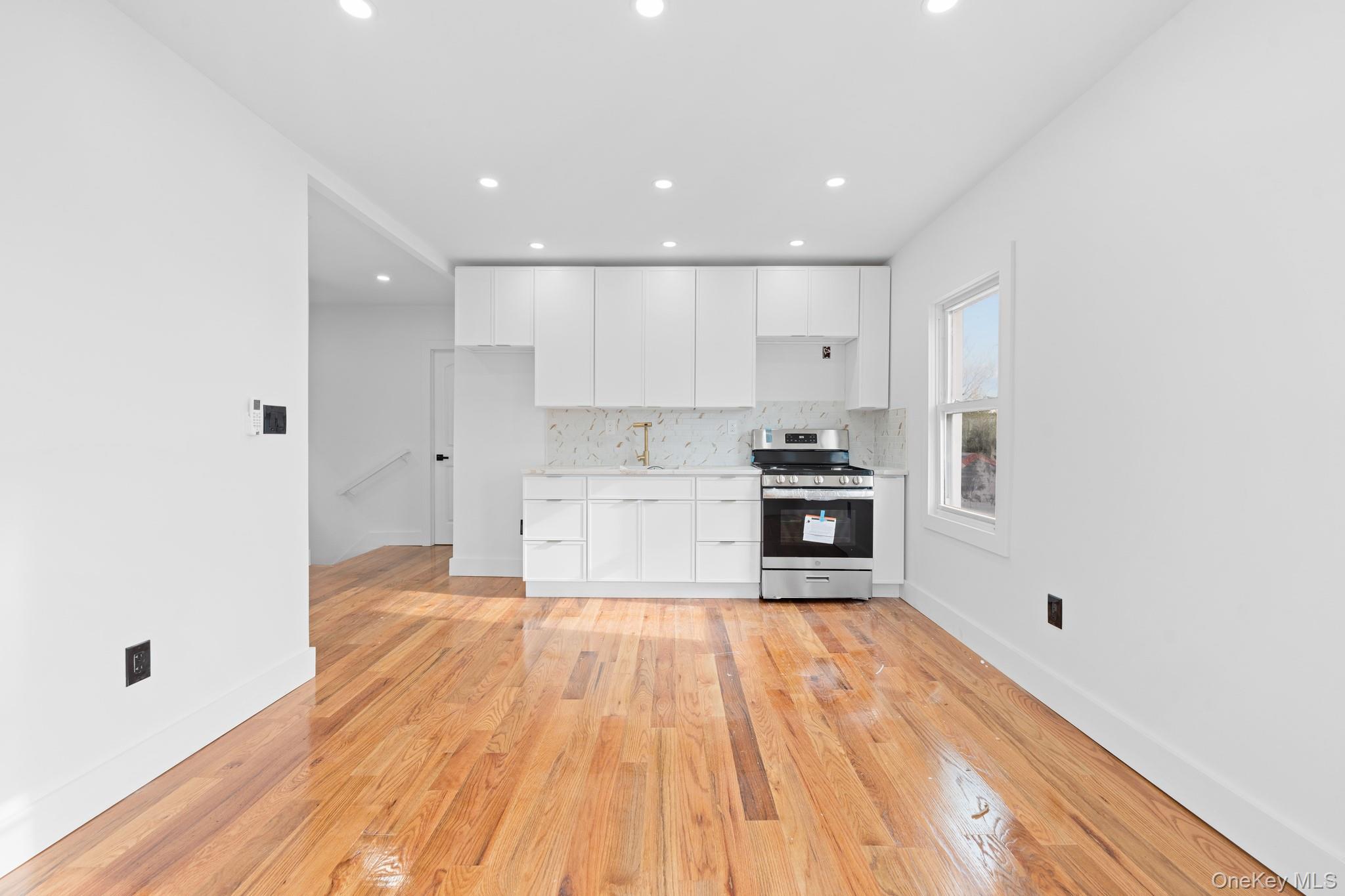 115-39 202nd Street Queens, NY 11412 - Photo 11 of 29 Kitchen featuring white cabinets, stainless steel range, tasteful backsplash, light wood-type flooring, and recessed lighting