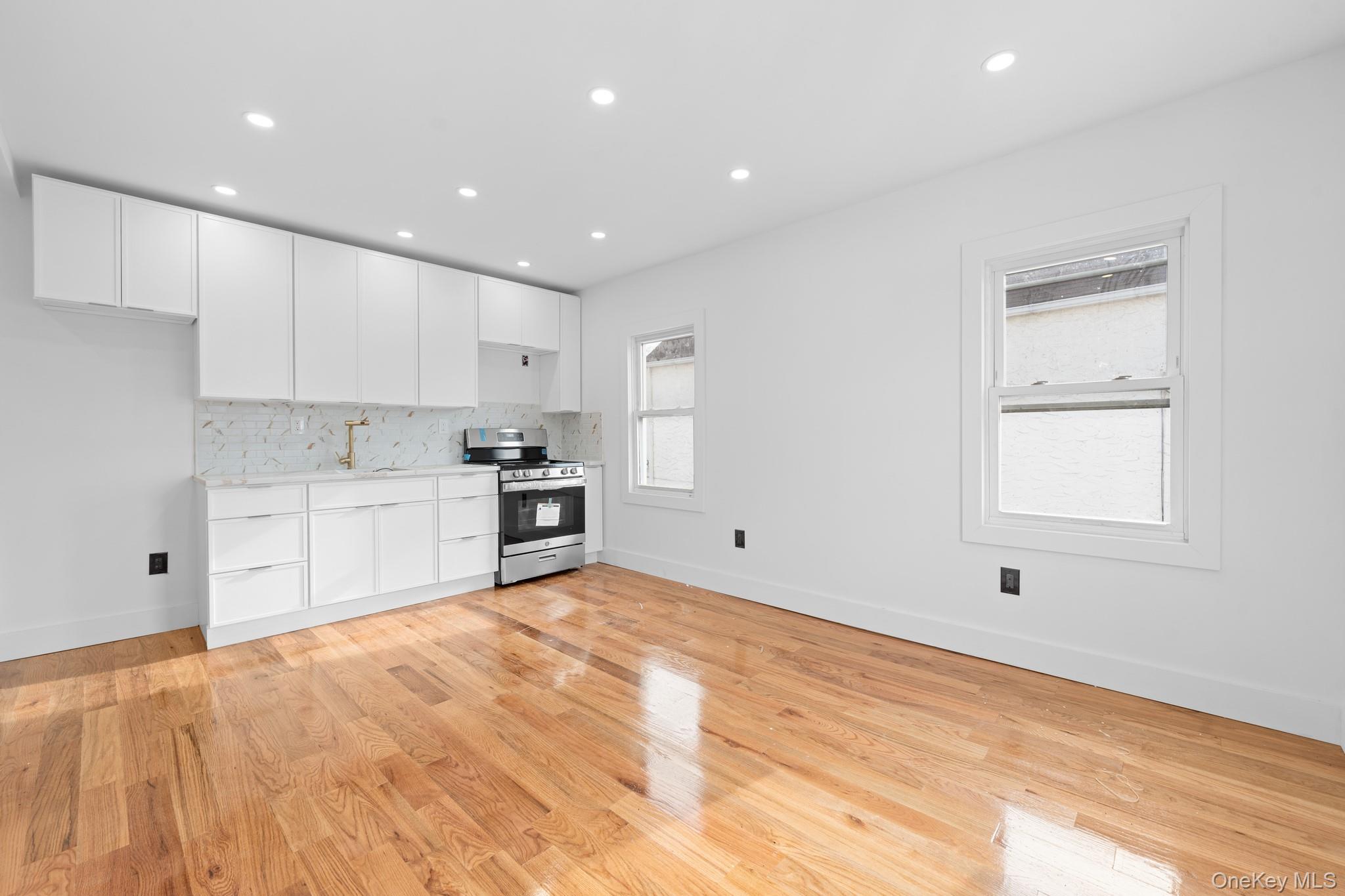 115-39 202nd Street Queens, NY 11412 - Photo 12 of 29 Kitchen featuring white cabinets, stainless steel range oven, light wood finished floors, recessed lighting, and decorative backsplash