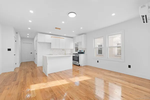 a large white kitchen with kitchen island a sink stainless steel appliances and cabinets