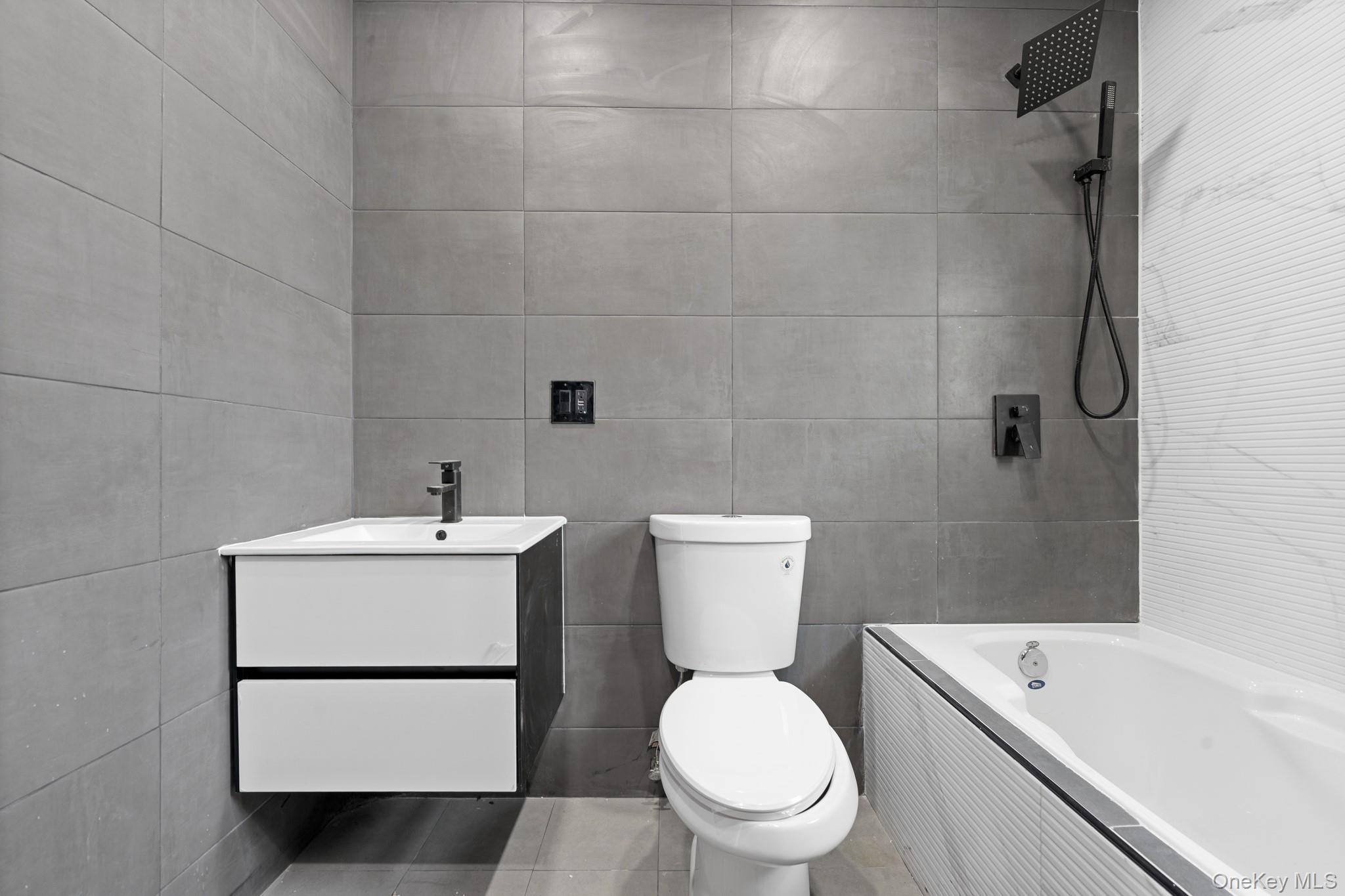 115-39 202nd Street Queens, NY 11412 - Photo 14 of 29 Bathroom with vanity, tiled shower / bath combo, tile walls, and tile patterned floors