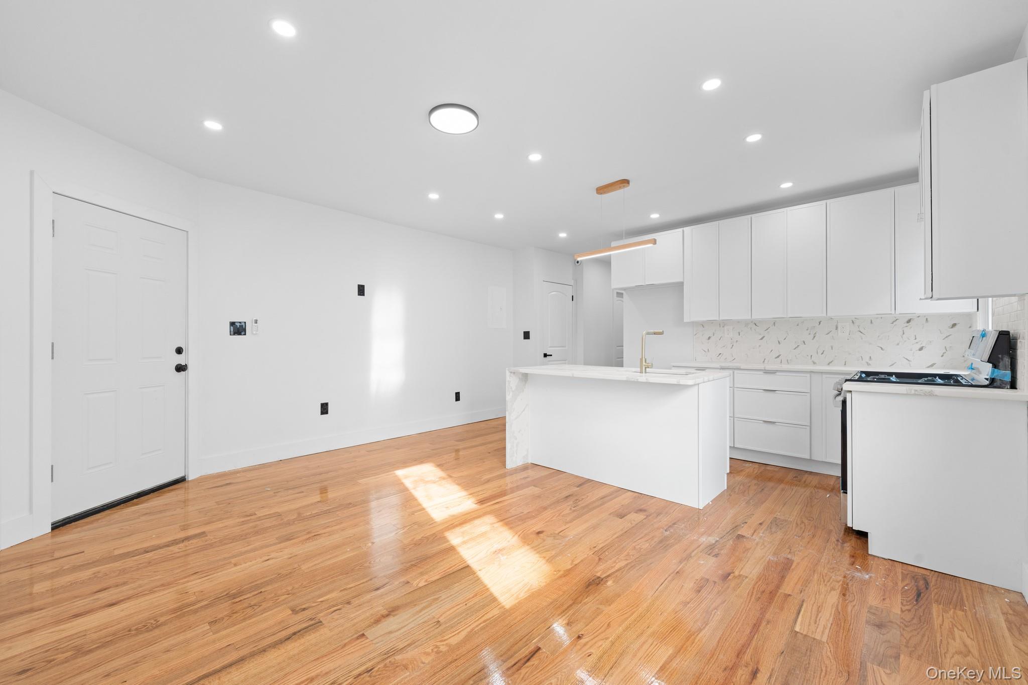 115-39 202nd Street Queens, NY 11412 - Photo 4 of 29 Kitchen with recessed lighting, a center island with sink, white cabinets, light wood-style floors, and range with gas cooktop
