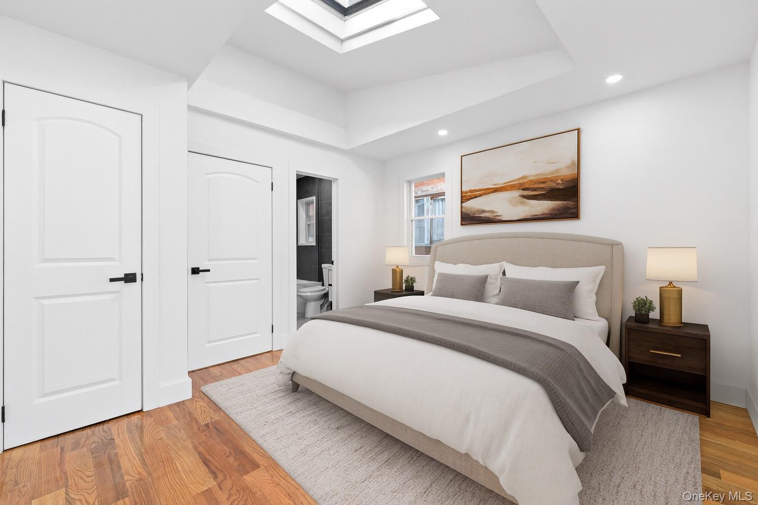 115-39 202nd Street Queens, NY 11412 - Photo 6 of 29 Bedroom featuring a skylight, light wood-style floors, connected bathroom, a tray ceiling, and recessed lighting