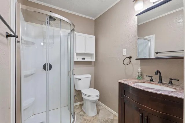 a bathroom with a granite countertop sink a toilet and a shower