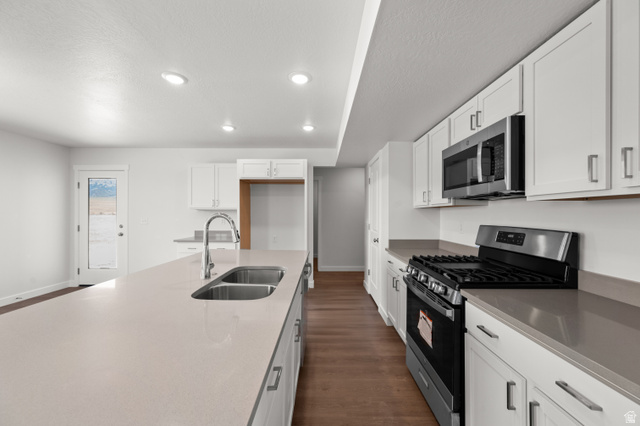 1554 Pheasant Road Eagle Mountain, UT 84005 - Photo 10 of 29 Kitchen featuring stainless steel appliances, white cabinetry, dark wood-style flooring, light stone countertops, and recessed lighting