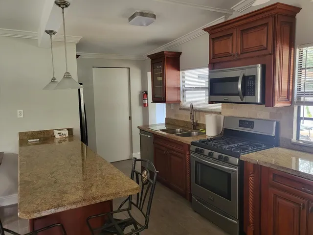 a kitchen with stainless steel appliances granite countertop a stove a sink and a microwave