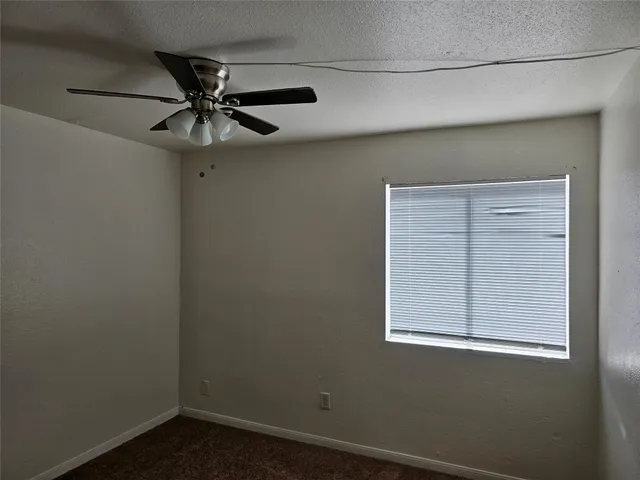 an empty room with a window and a fan