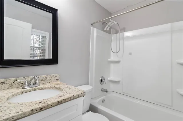 a bathroom with a granite countertop sink a mirror and a bathtub