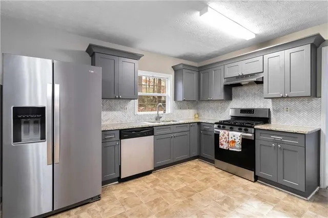 a kitchen with granite countertop a stove sink and refrigerator