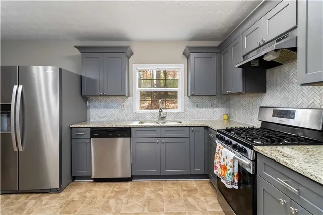 a kitchen with stainless steel appliances granite countertop a sink stove and refrigerator