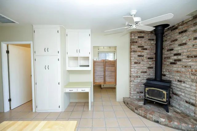 a view of an empty room with wooden floor and fan