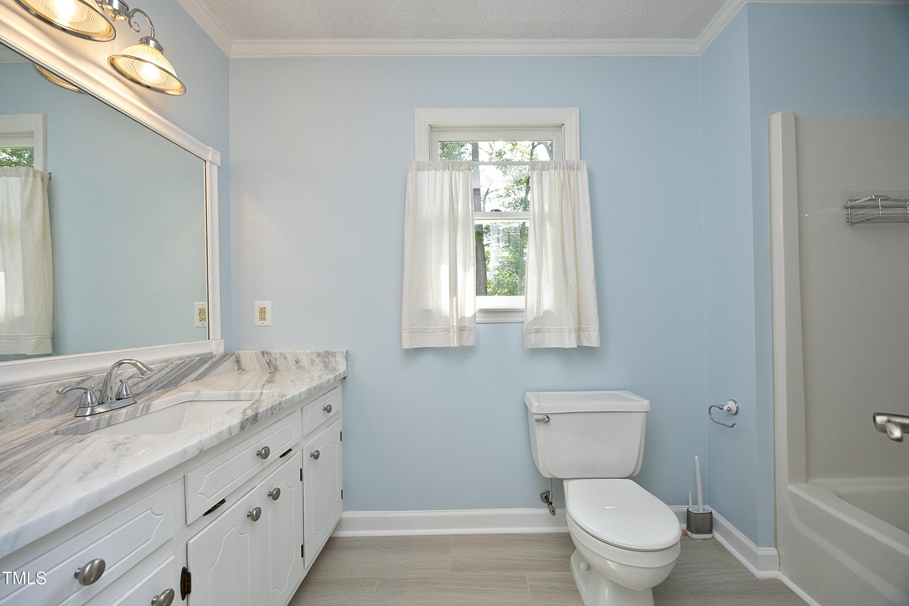 409 Glaive Drive Durham, NC 27703 - Photo 28 of 35 a bathroom with a granite countertop toilet a sink a mirror and a window