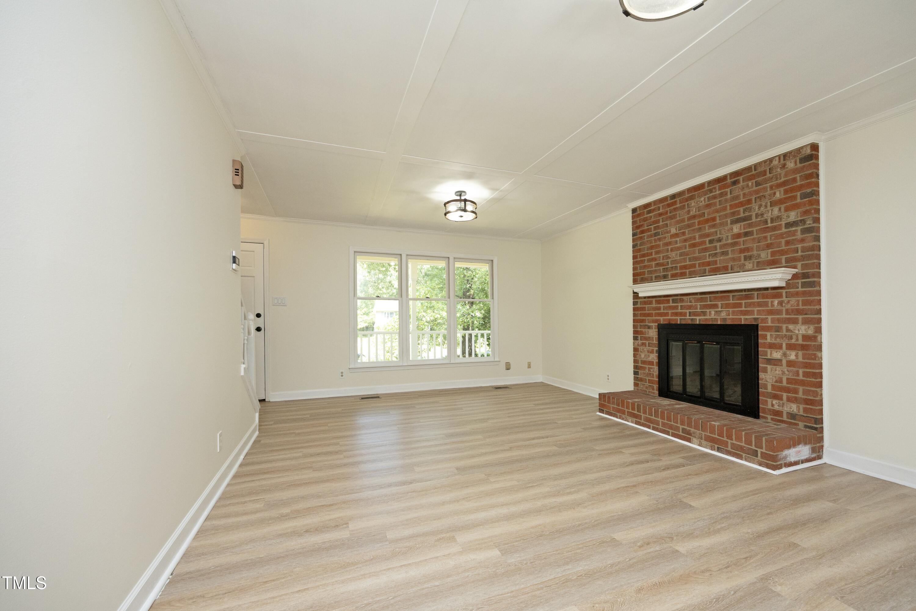 409 Glaive Drive Durham, NC 27703 - Photo 8 of 35 a view of an empty room with wooden floor fireplace and a window