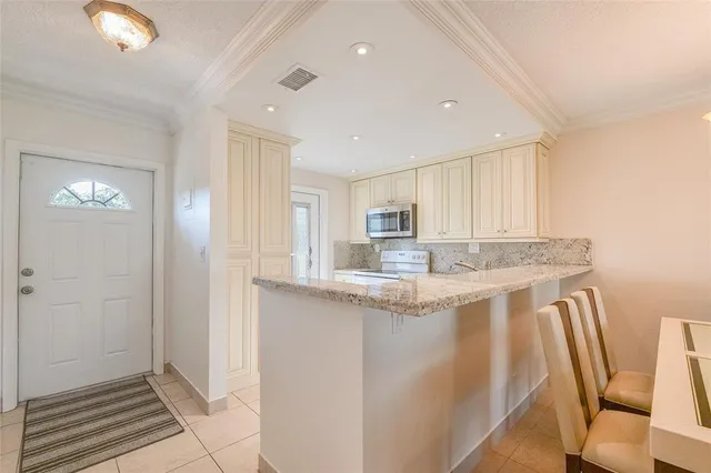 a view of living room with granite countertop white cabinets and chandelier