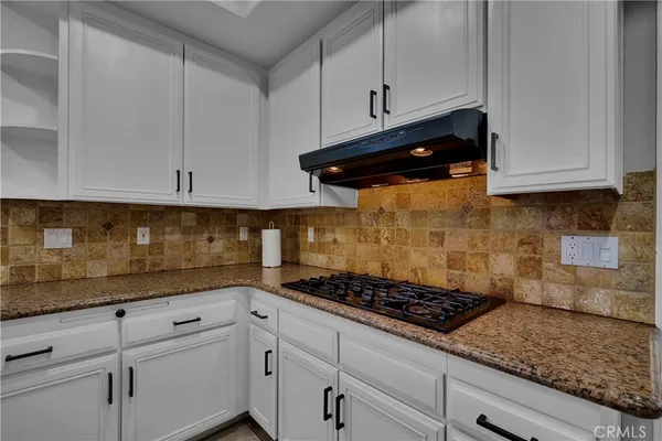 a kitchen with granite countertop a sink a counter top space stainless steel appliances and cabinets